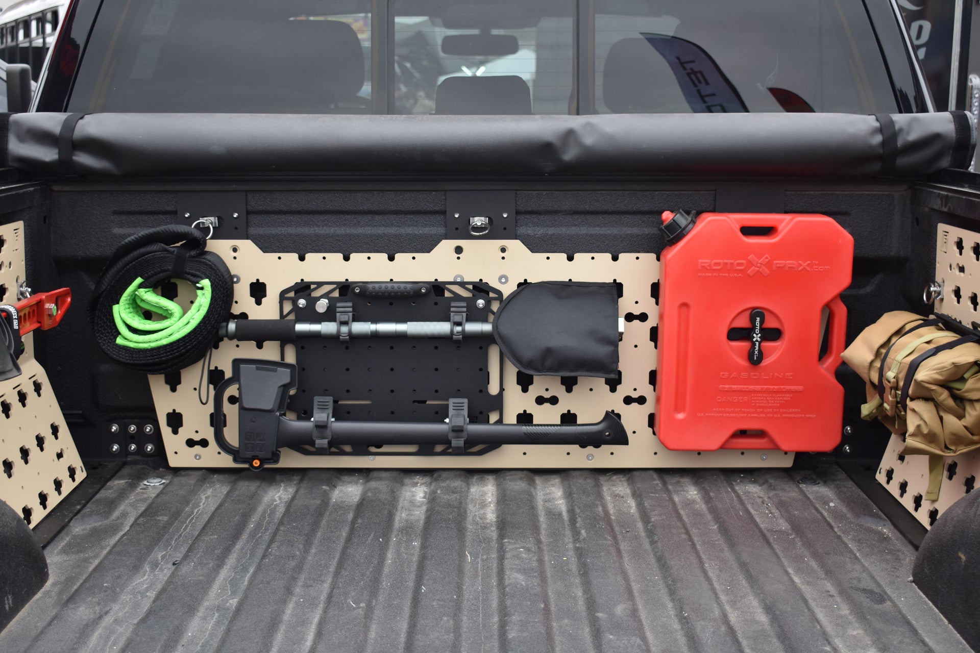 Forged Authority Tan MOBUL F-150 Header Panel, used to securely store tools and gear in your truck bed, featuring storage of a snatch strap, our RotoPax Adapter accessory, and our Tool Board securing a shovel and axe.