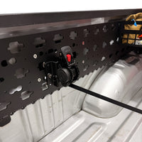 MOBUL Retractable Ratchet Strap Mount, strap extended, on a MOBUL panel in a truck bed.
